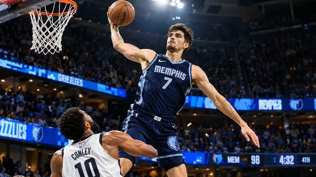 Memphis basketball player in a dark blue jersey jumping for a one-handed dunk over a defender in a packed arena.
