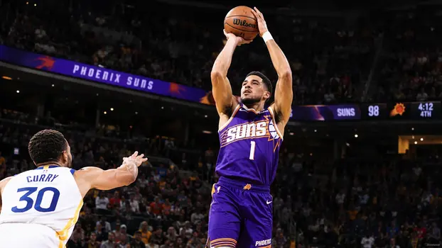 Phoenix Suns basketball player in a purple and orange jersey jumping to shoot a three-pointer during an NBA game.